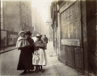 photograph; silver gelatin print - A woman carrying a toddler with a young girl in Drury Lane